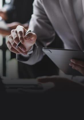 A man looks at something in his tablet, pen in his hand