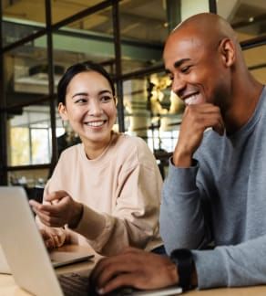People cheerily discuss something they see on their laptops